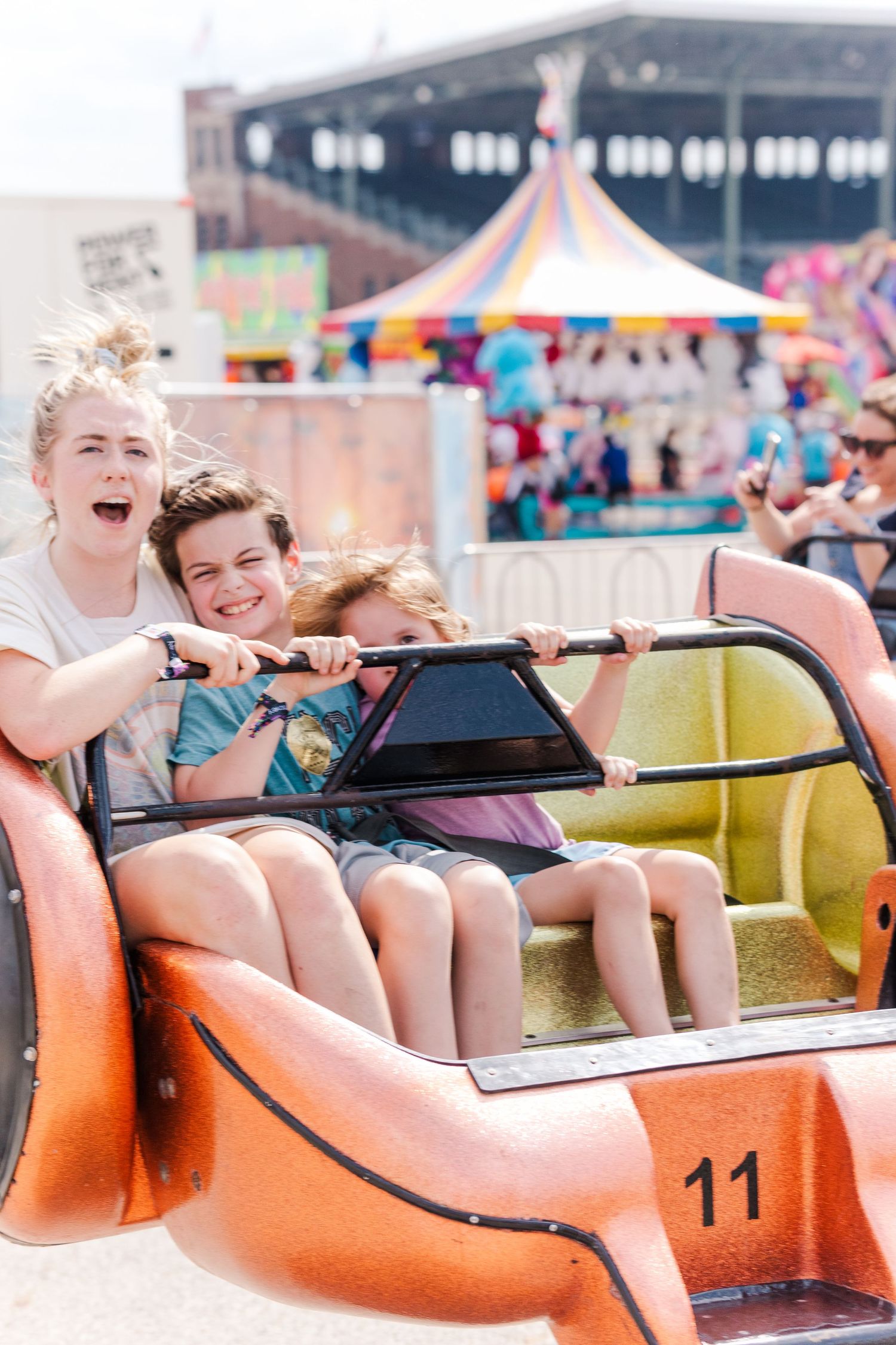 Carnival goers enjoying a fast-spinning orange ride at an outdoor fair.