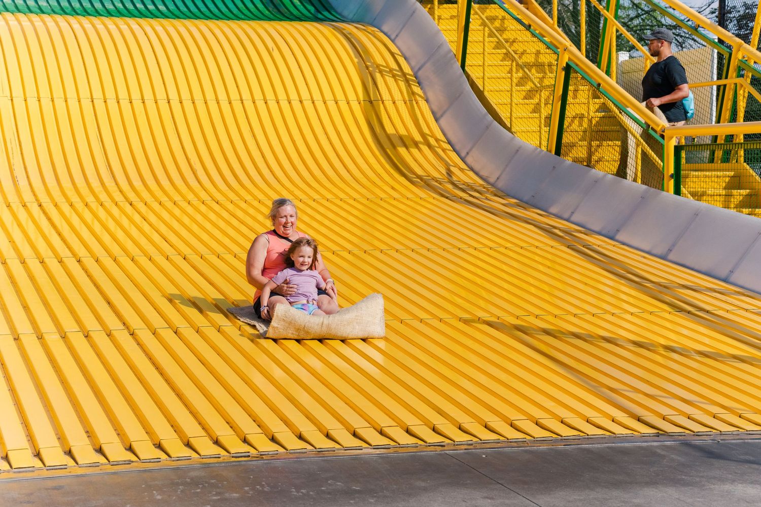 Yellow and green giant slide with multiple lanes at an outdoor carnival.