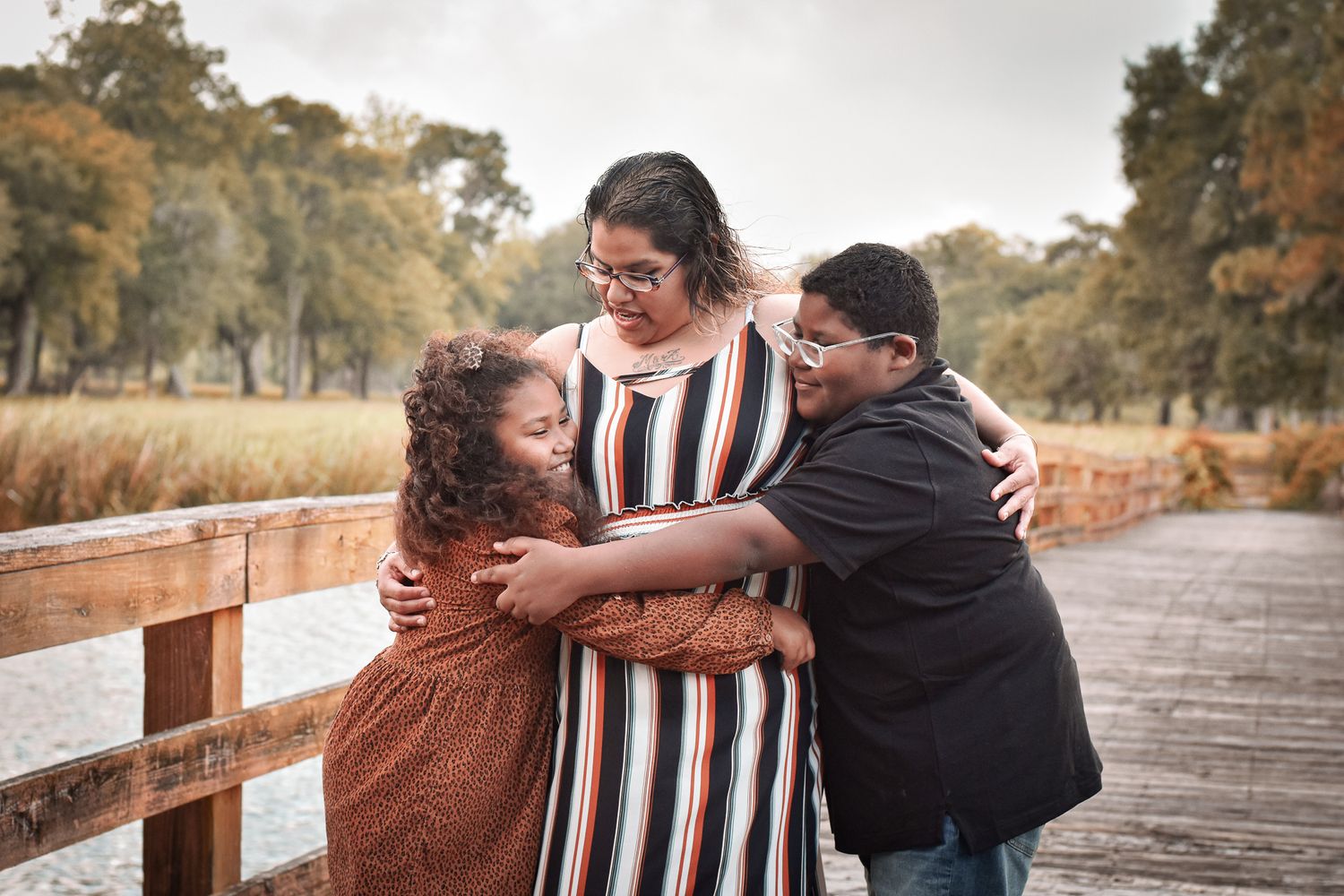 Playful family moment captured on wooden bridge during outdoor photoshoot.