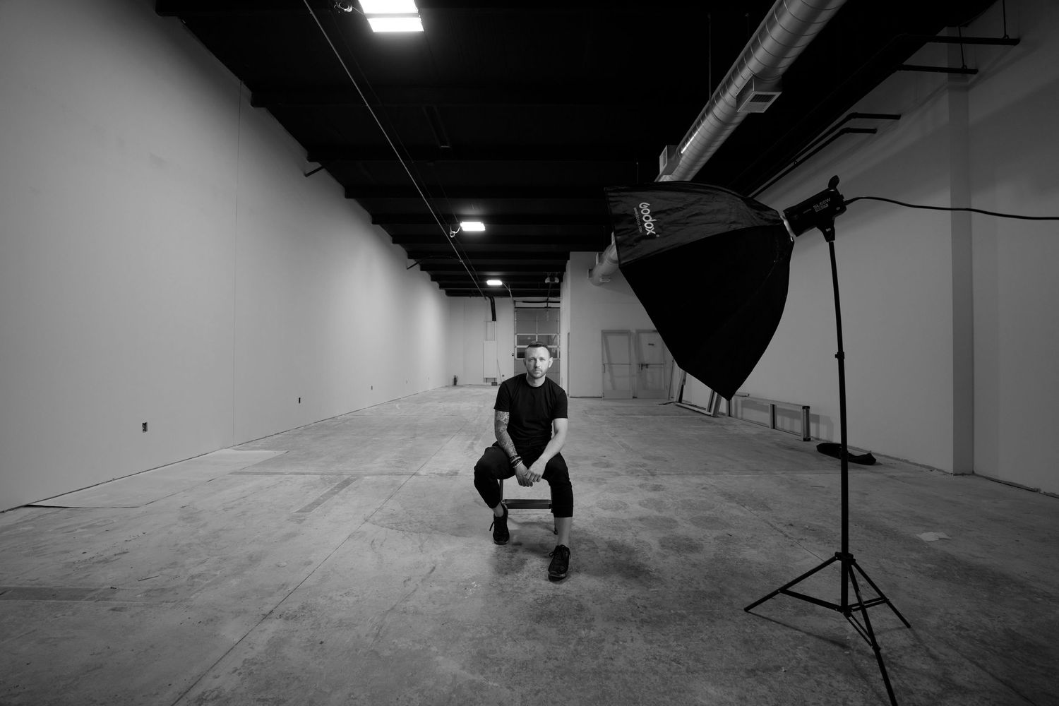 Photography studio setup with lighting equipment and silhouette in empty warehouse space.