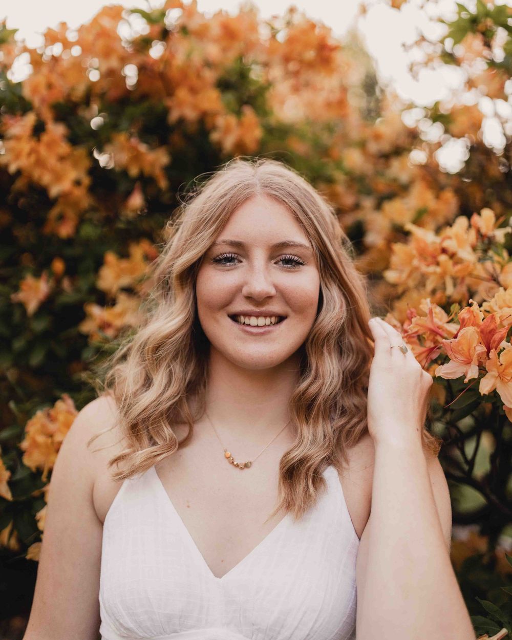 Senior portrait of female smiling in front of orange flowers at the Dubuque Iowa Arboretum and Botanical Gardens