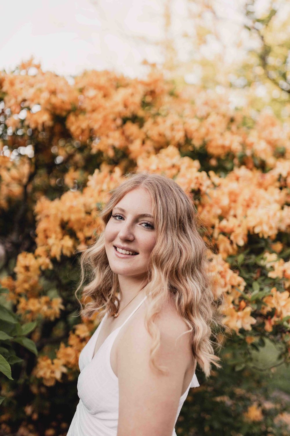 Senior portrait of female smiling in front of orange flowers at the Dubuque Iowa Arboretum and Botanical Gardens