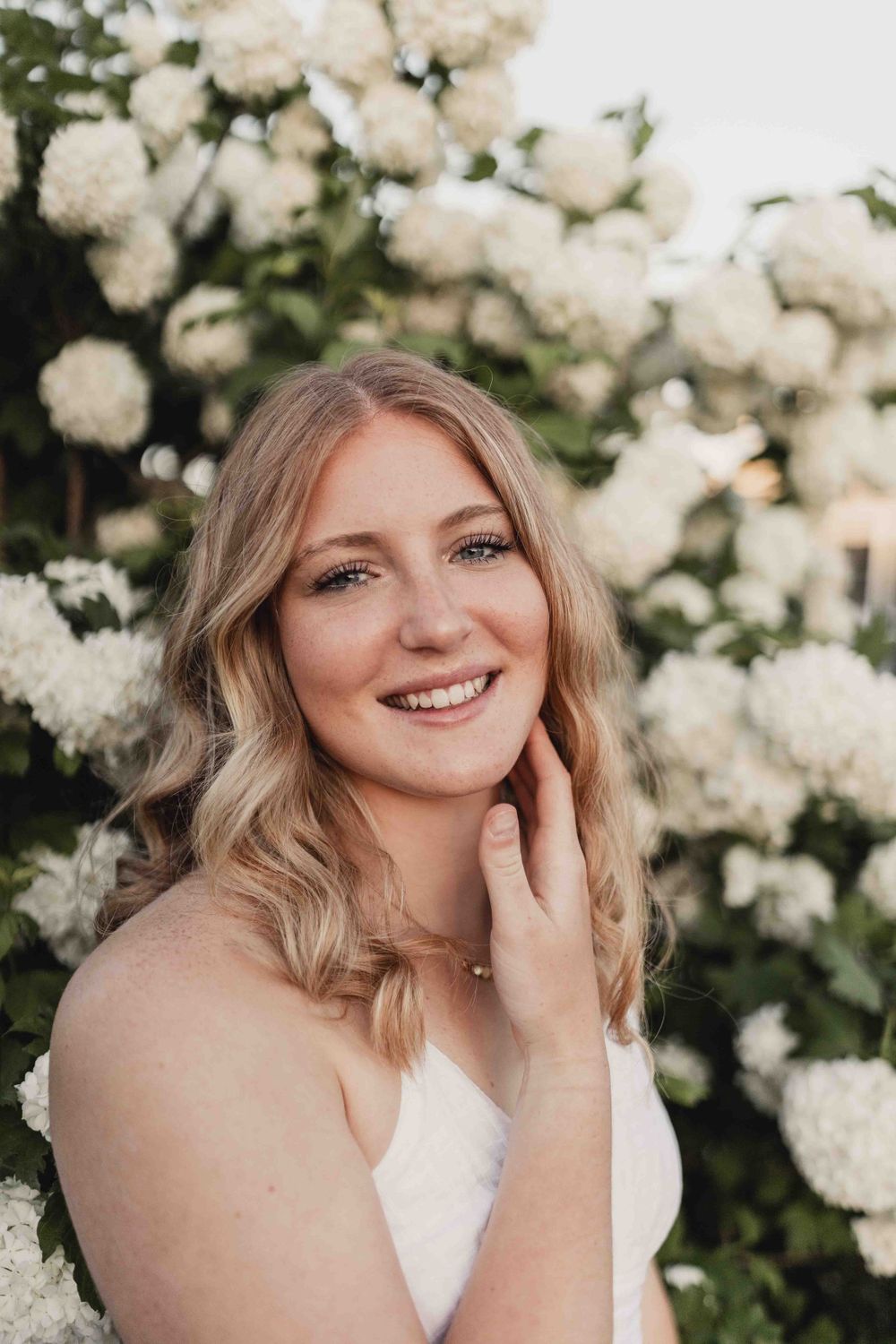 Senior portrait of female smiling in front of white flowers at the Dubuque Iowa Arboretum and Botanical Gardens