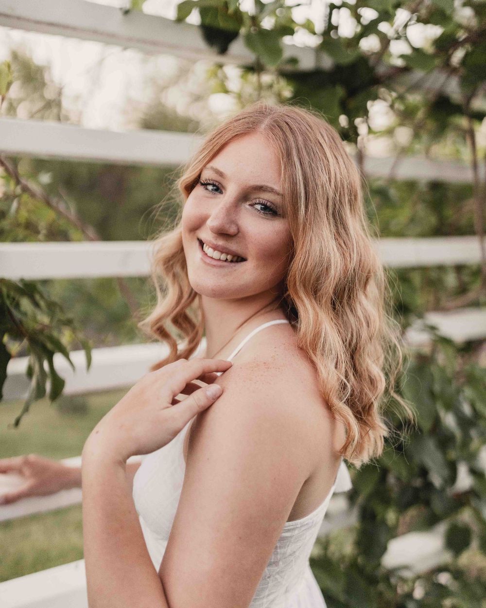 Senior portrait of female smiling in front of white flowers at the Dubuque Iowa Arboretum and Botanical Gardens