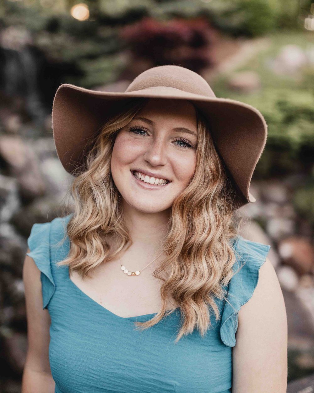 Senior portrait of female wearing a hat smiling outdoors at the Dubuque Iowa Arboretum and Botanical Gardens