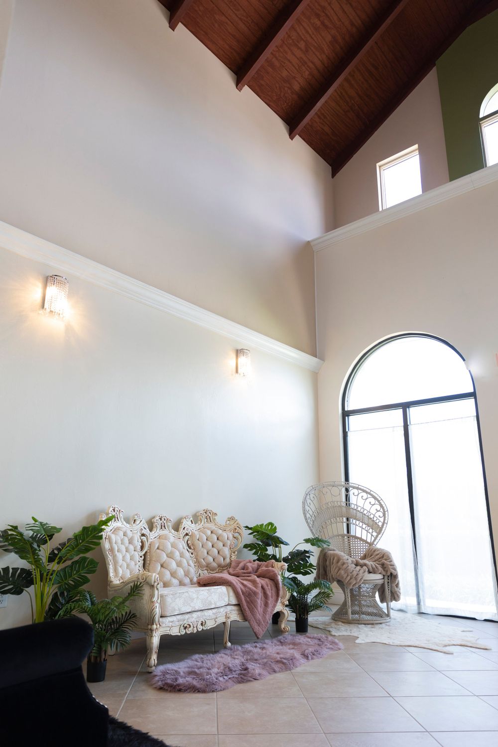 Bright interior with vaulted wooden ceiling, arched doorway and peacock chair.