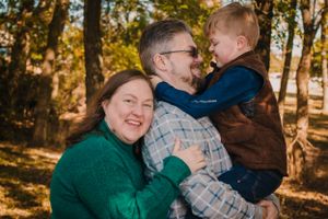 A family shares a joyful moment together outdoors in autumn sunshine.