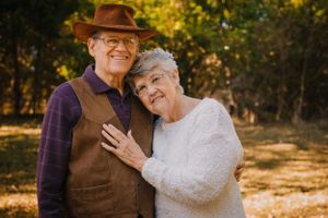 An older couple embraces outdoors during a fall photoshoot.