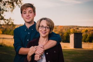 A mother and son embrace while posing for a portrait at sunset.