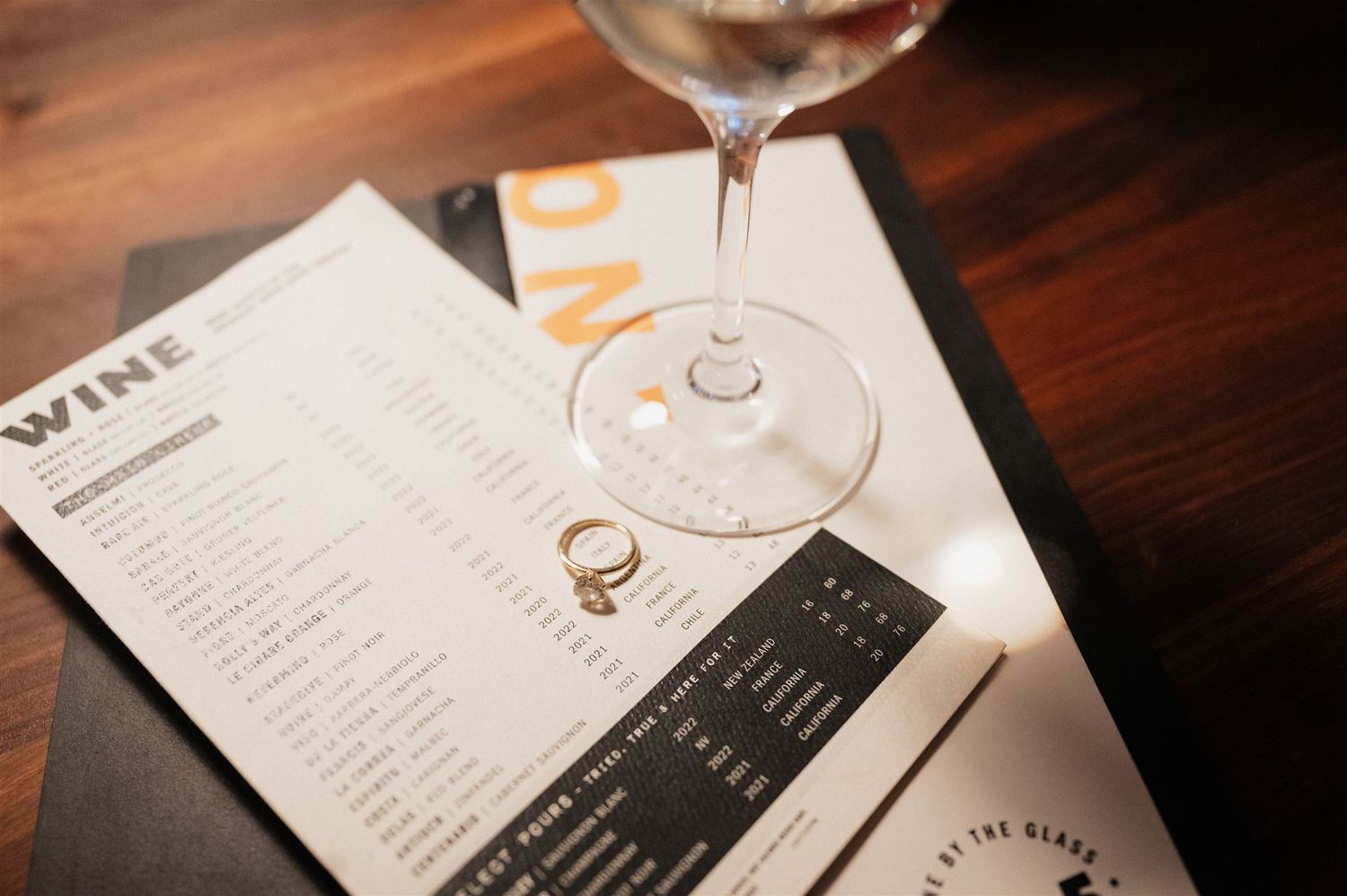Wine glass and menu on dark wooden table at upscale restaurant.