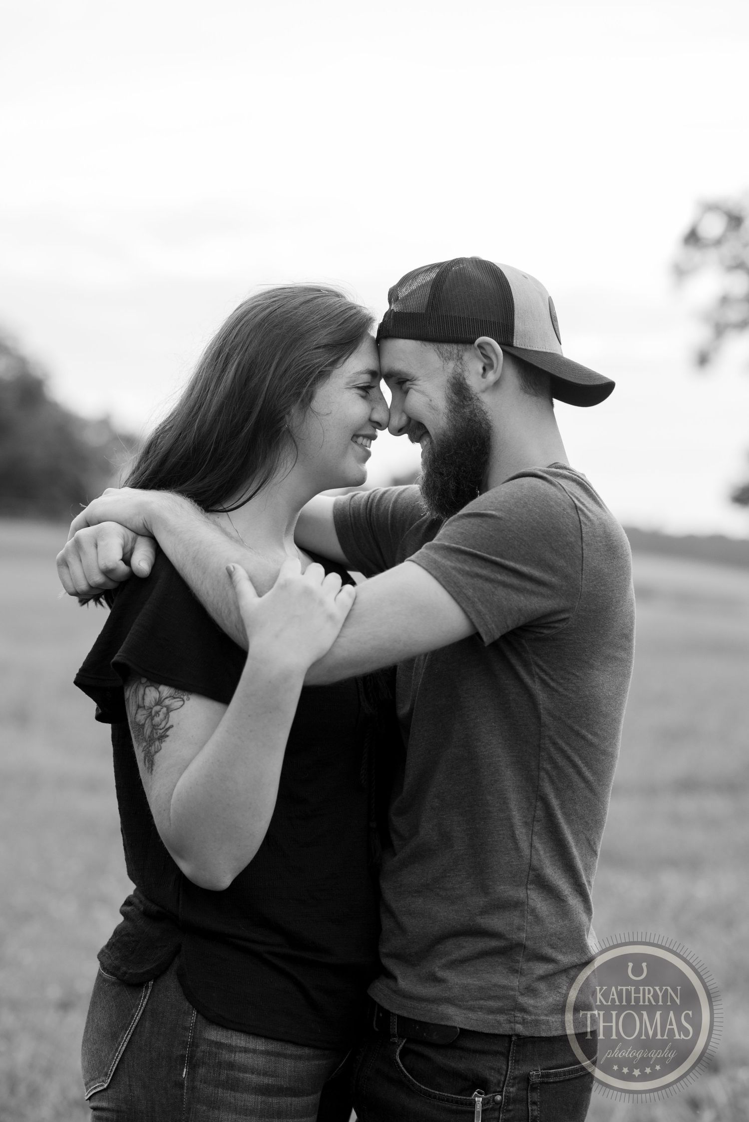 A black and white portrait of a couple in an intimate embrace outdoors.