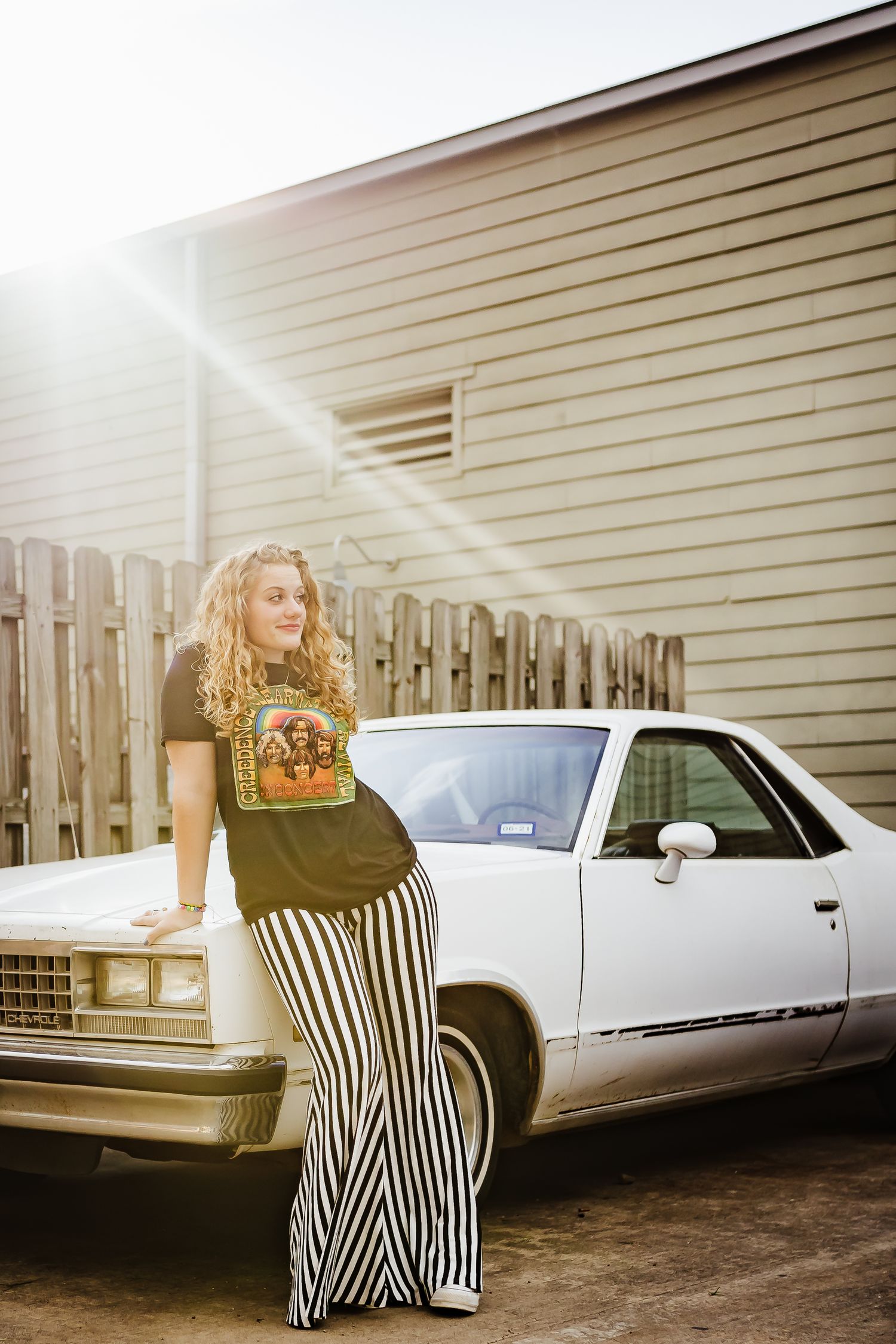 Retro-styled portrait with vintage car and striped maxi skirt in warm sunlight.