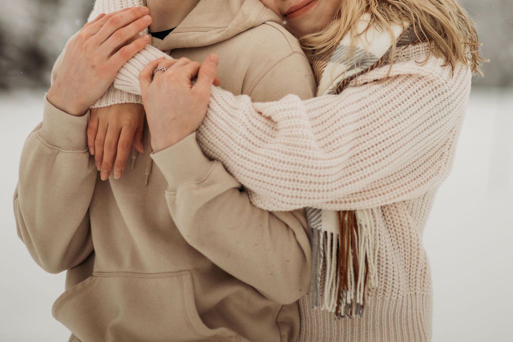 Couple in cozy winter sweaters sharing an intimate embrace in soft lighting.