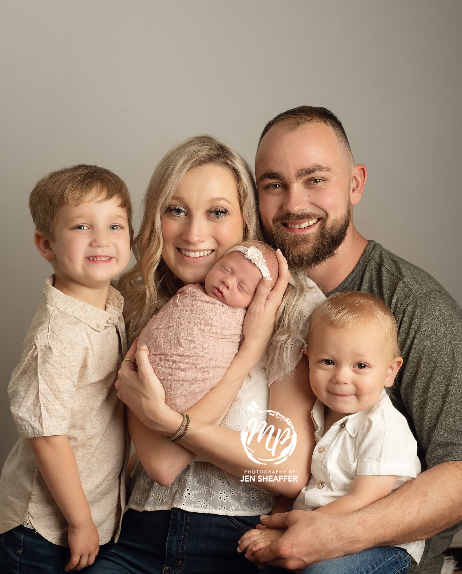 Family in newborn session with siblings and parents white wall natural