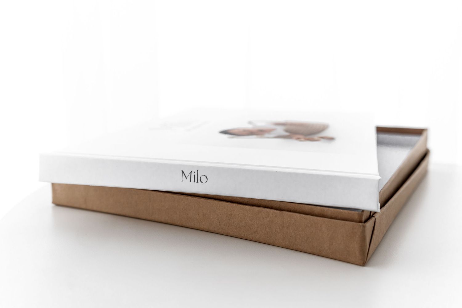 White hardcover photo album stacked on brown protective box.