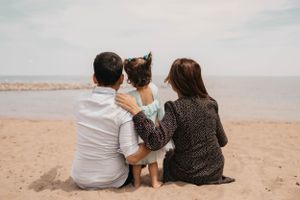 A family sits together on the beach watching the water on a peaceful afternoon.