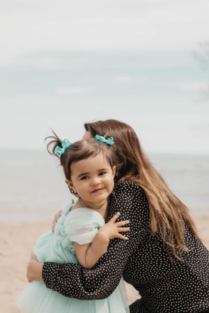 A sweet embrace shared between parent and child on a cloudy beach day.