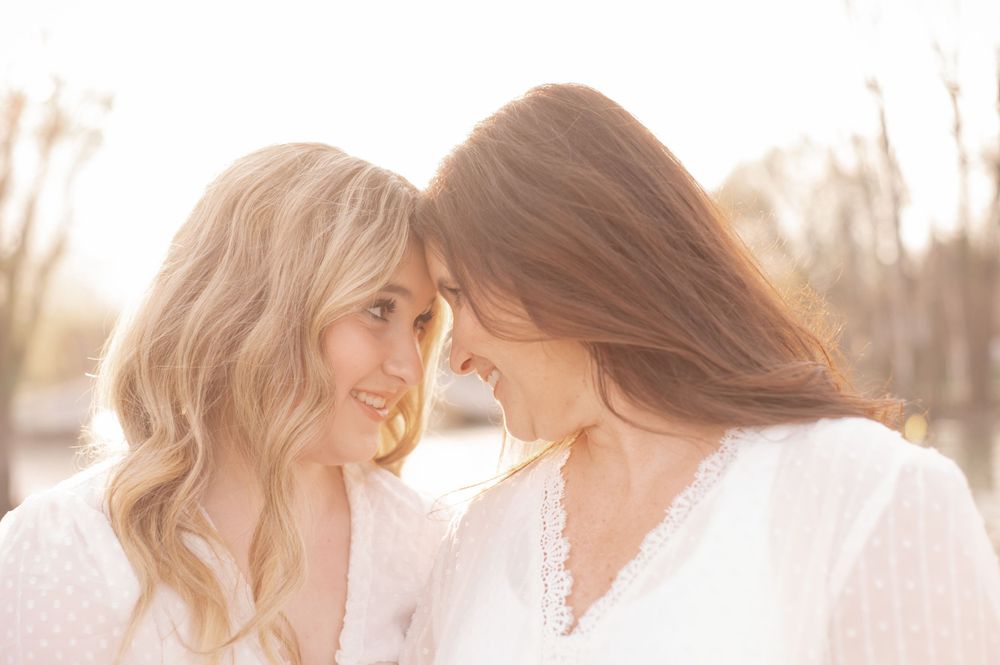 Two people in white outfits share an intimate moment in soft sunlight.
