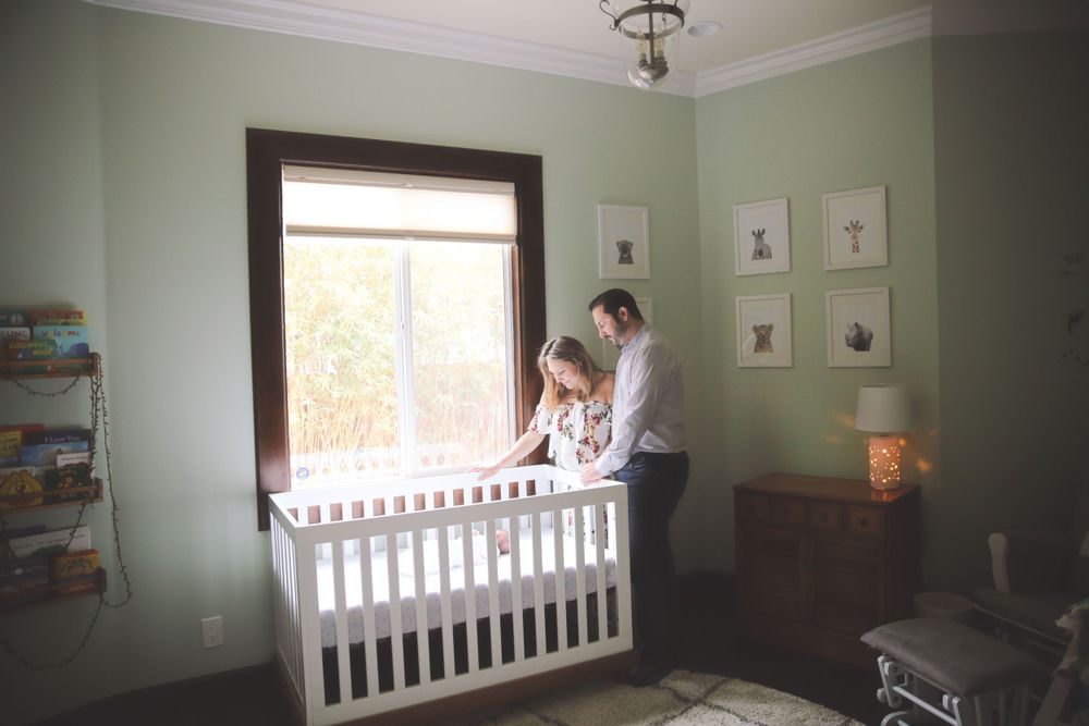 Parents admiring newborn in crib with affection