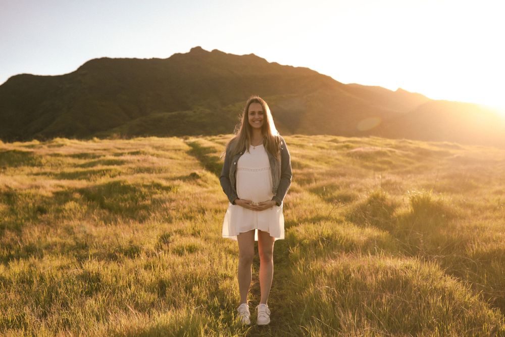 A silhouette stands in a golden field at sunset with mountains in the background and warm sunlight creating a magical glow.