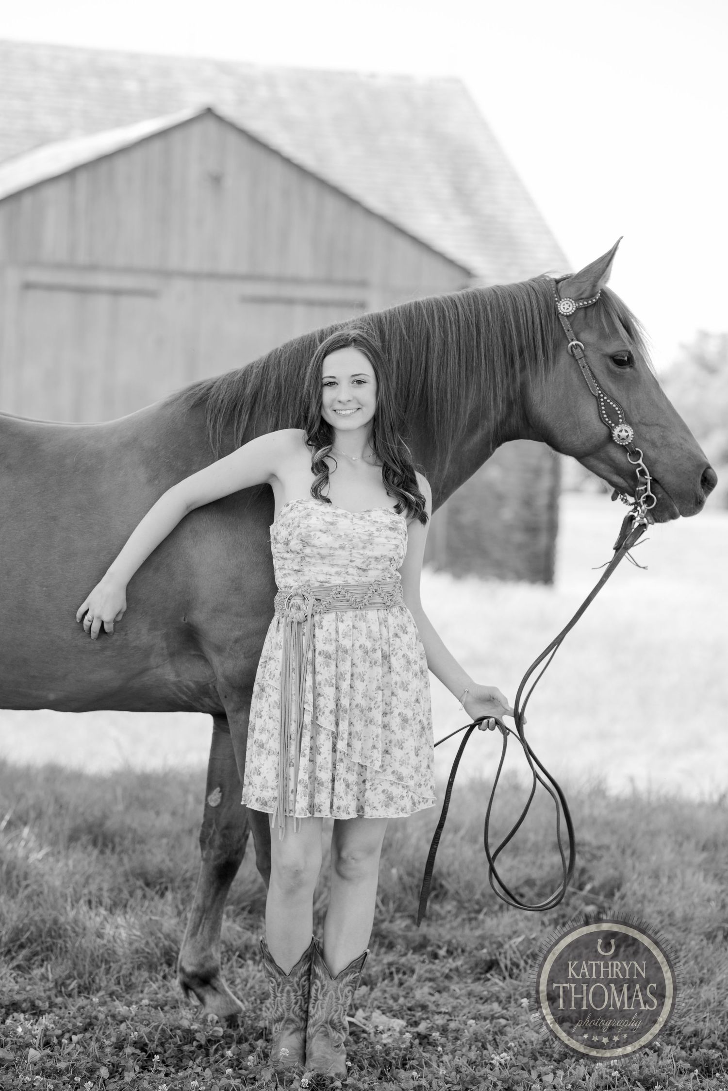 A black and white portrait with a horse and rider against a rustic barn setting.