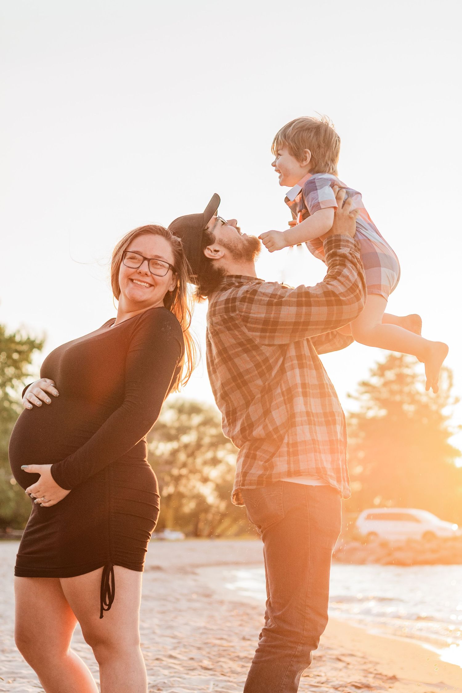 Playful family moment at sunset on beach with golden light.