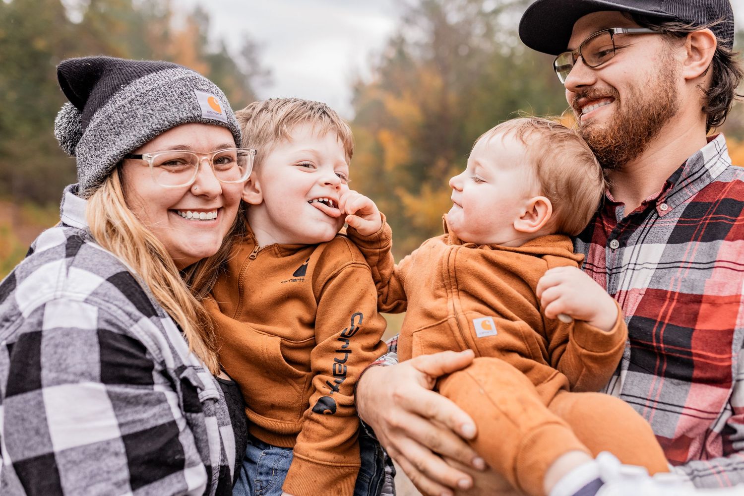 A close-up family portrait on an autumn trail with fall colors in the background.