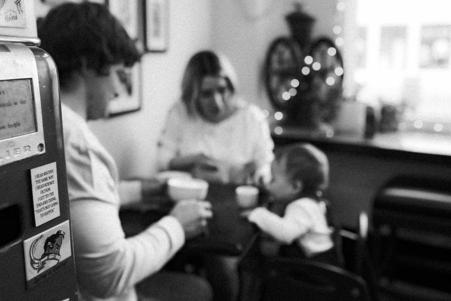 Family enjoying hot drinks together at a cozy cafe table in black and white.