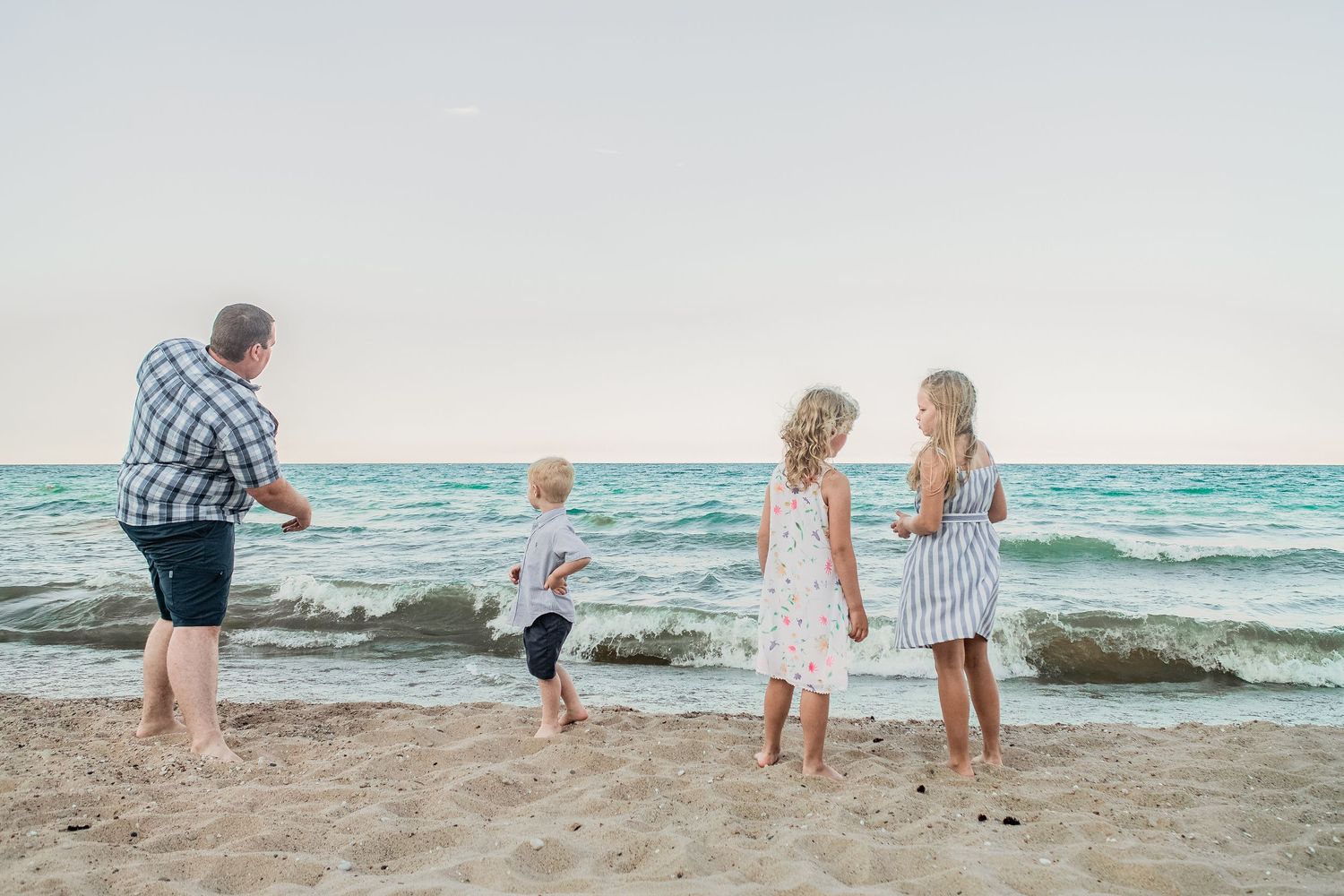 People enjoy a playful moment together on a beach with waves rolling in.