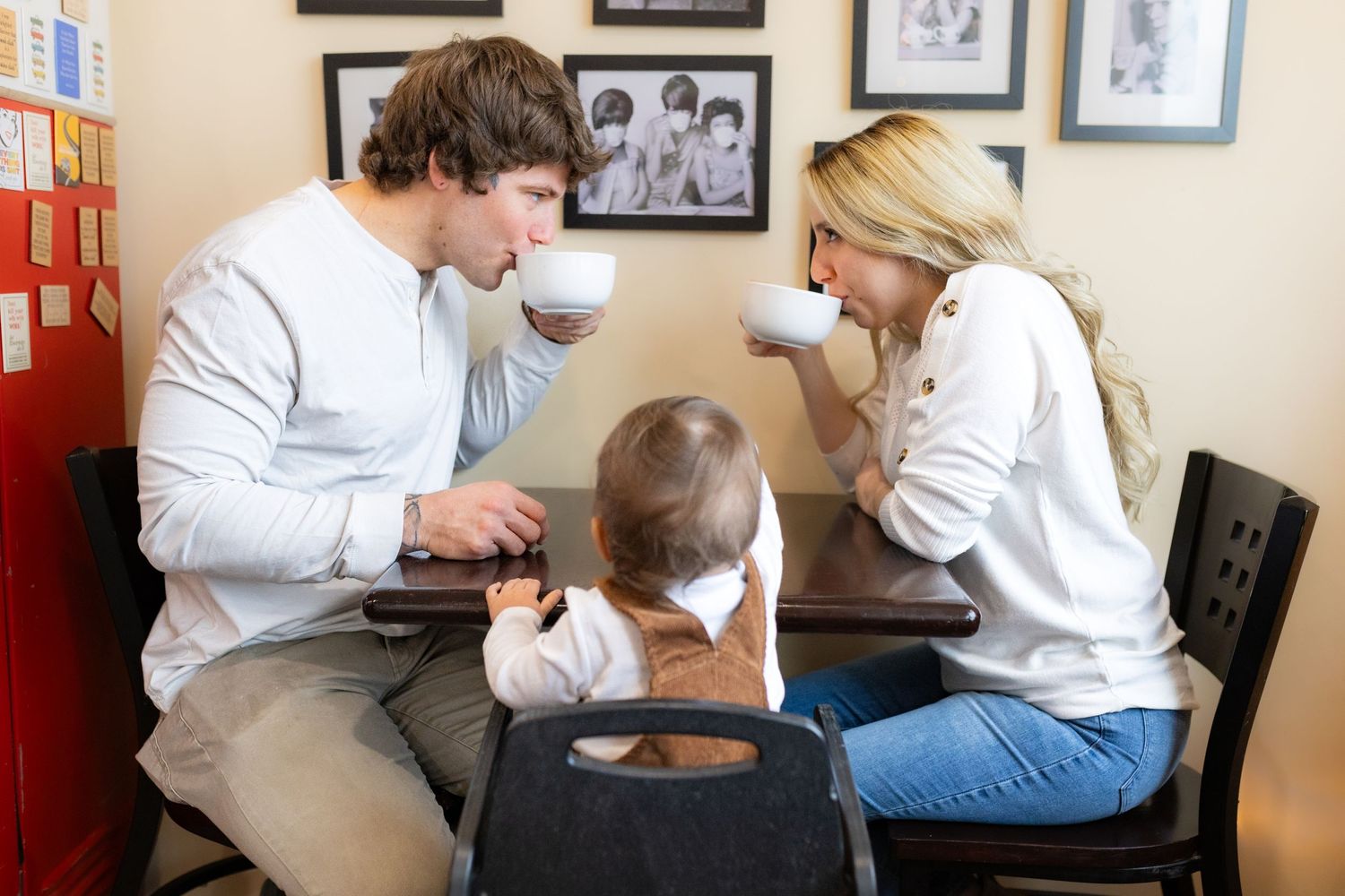 Family of three sharing drinks together at a small cafe table.