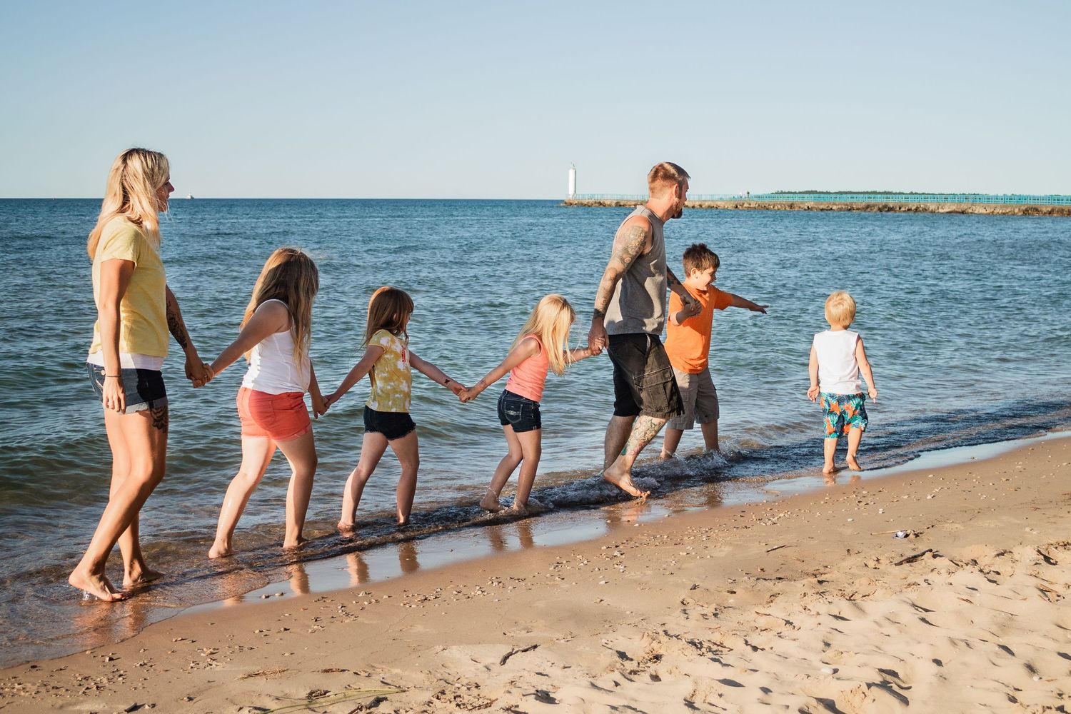 Family walking together along sandy beach shoreline at sunset.