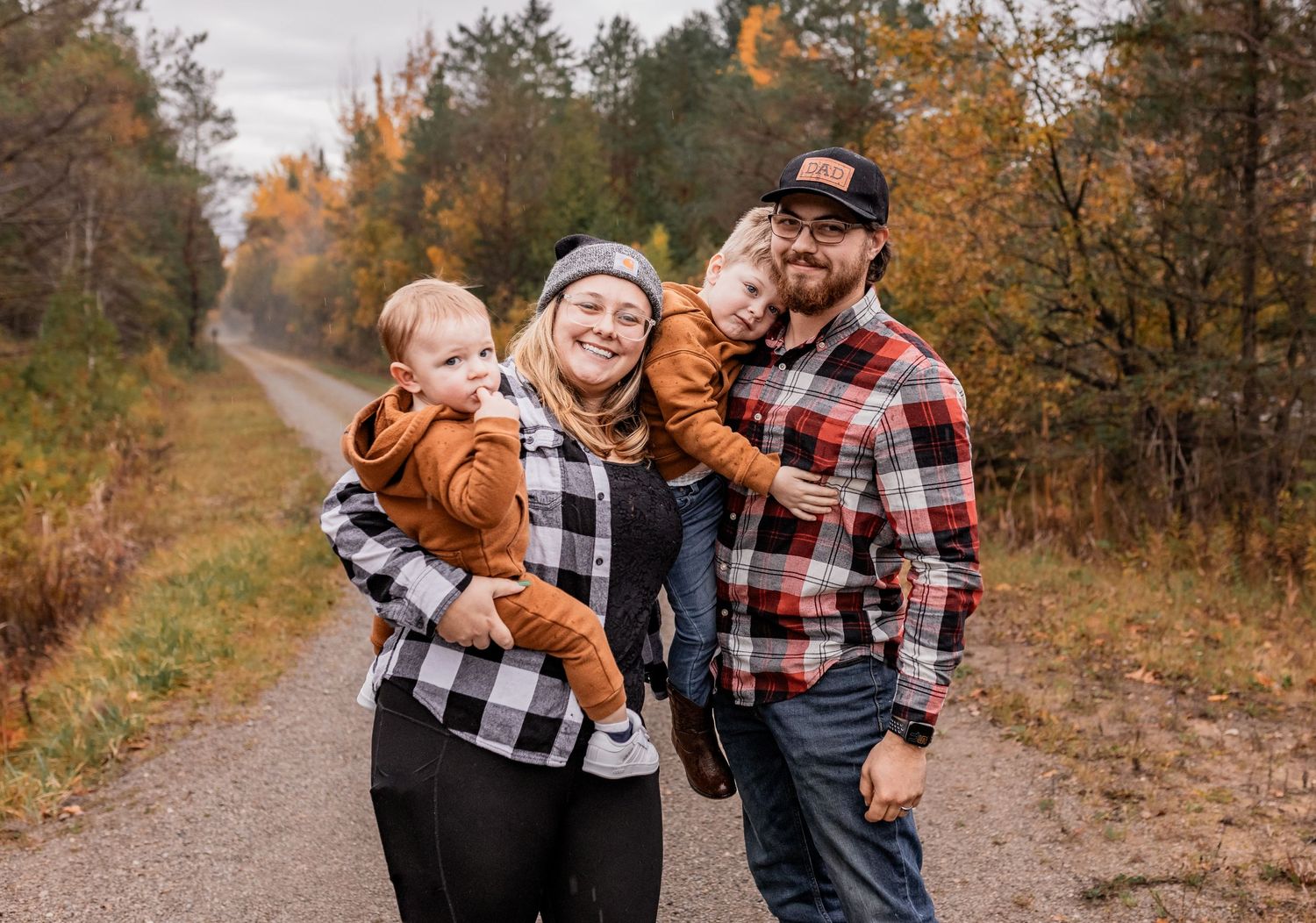 A fall family portrait on a tree-lined path with autumn colors in the background.