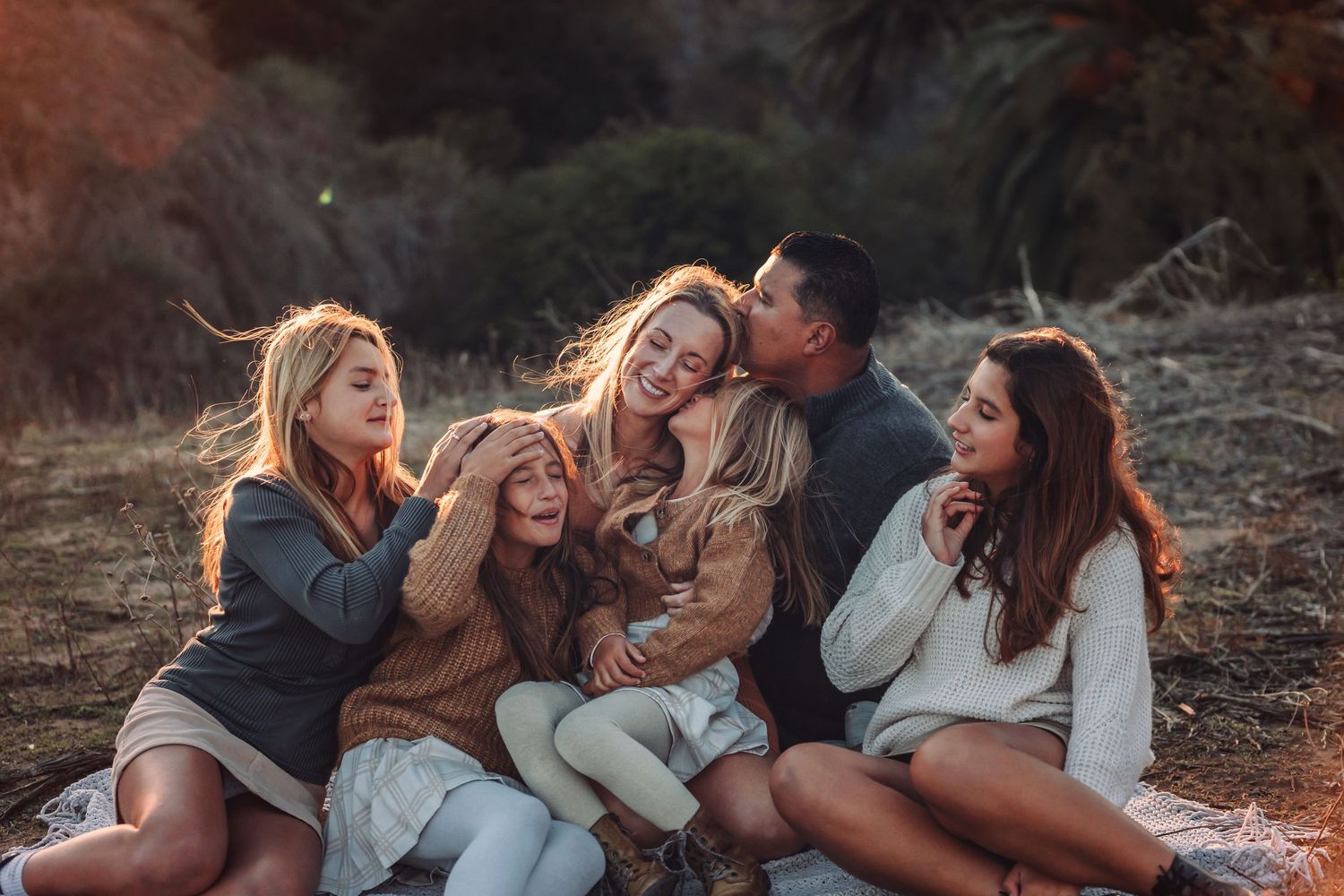 Group of friends laughing together outdoors at sunset.