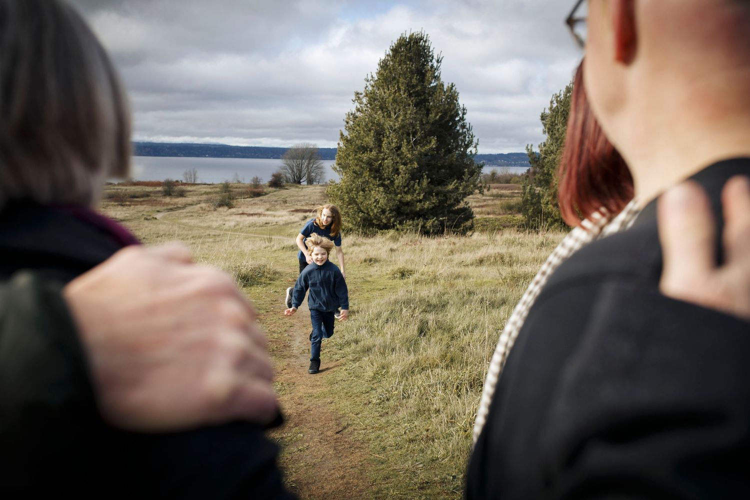 seattle lifestyle photographer: two boys run towards their parents and grandparents at Discovery Park in Seattle