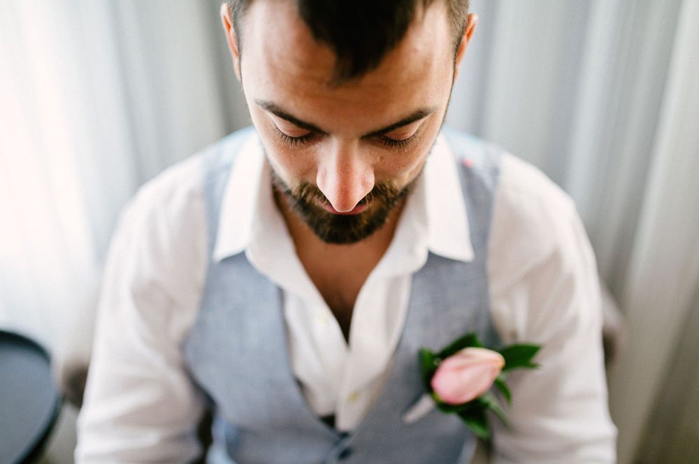 Close up portrait of groom in grey vest with pink boutonniere.