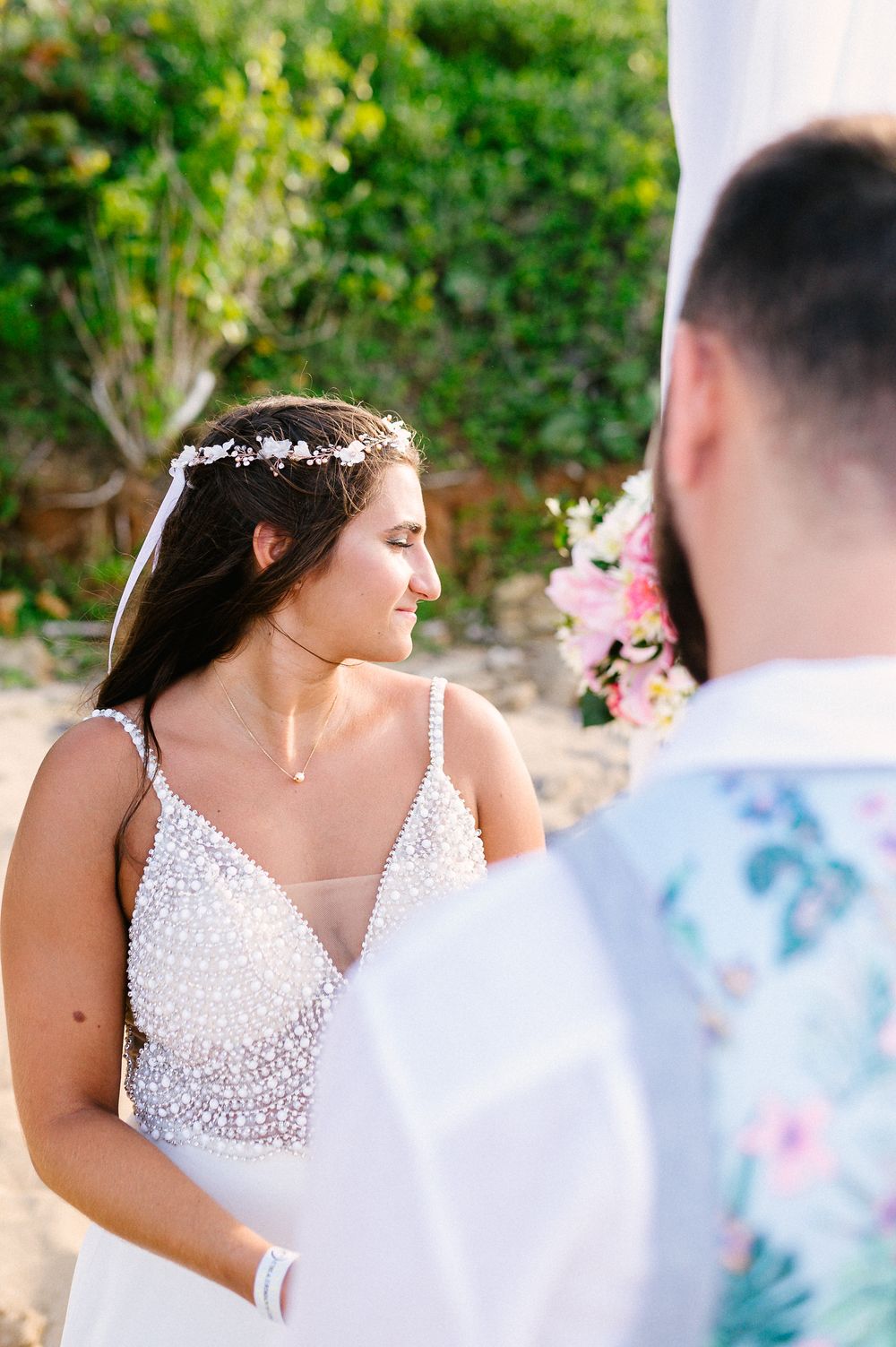 Sun-lit portrait of bride in sequined dress wearing delicate floral crown.