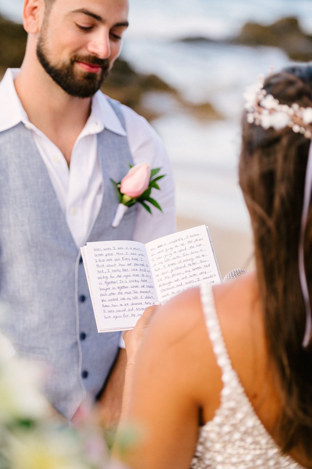 A romantic moment during a beach wedding ceremony as personal vows are exchanged.