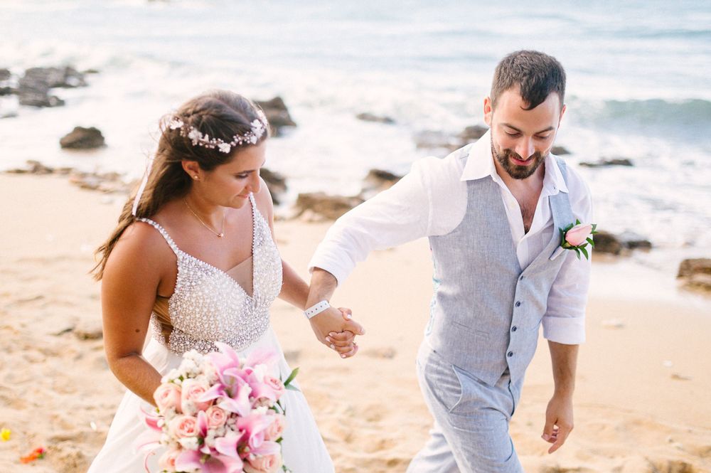 A joyful moment captured during a beach wedding with a pink bouquet.