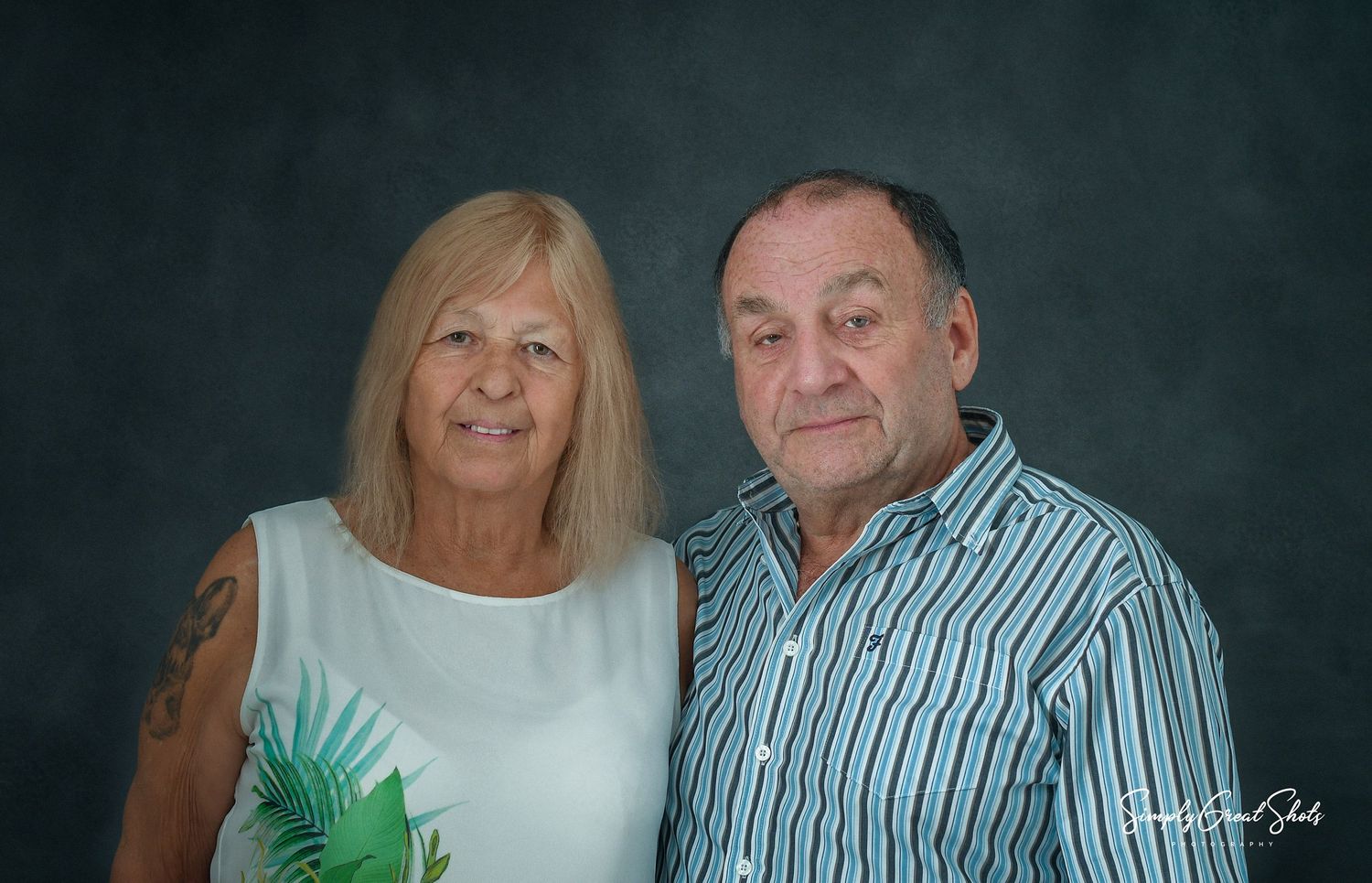 An elderly couple pose for the camera in a studio portrait photography session.