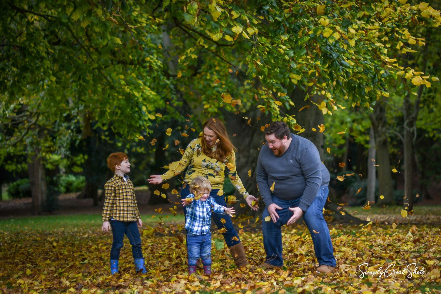 A family photoshoot - having fun throwing leaves into the air in Autumn