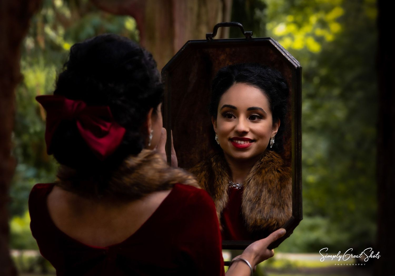 An asian lady looking at herself in a mirror from an outdoor photoshoot