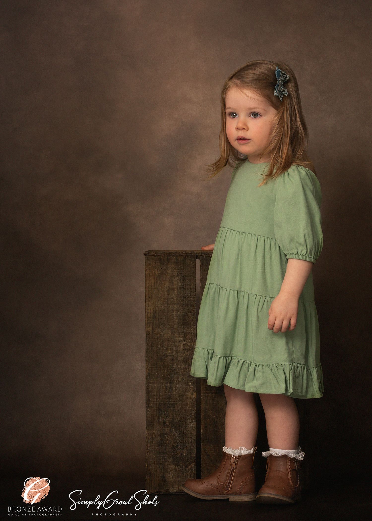 A portrait photograph of a little girl in a green dress