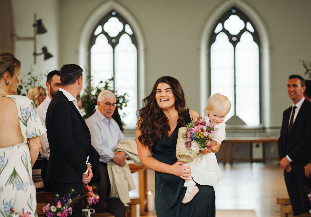 Wedding ceremony in progress inside historic church with gothic arched windows.