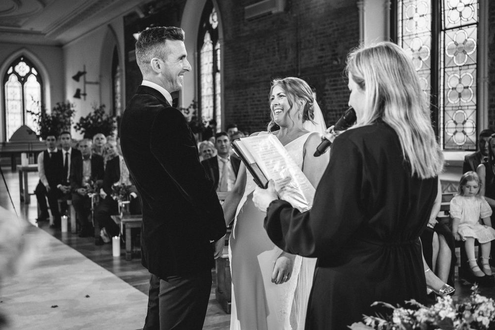 Wedding ceremony taking place in traditional church with gothic architecture and stained glass windows.