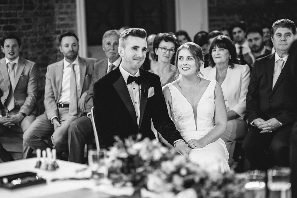 Elegant wedding ceremony in brick chapel with gothic windows and formal decor.
