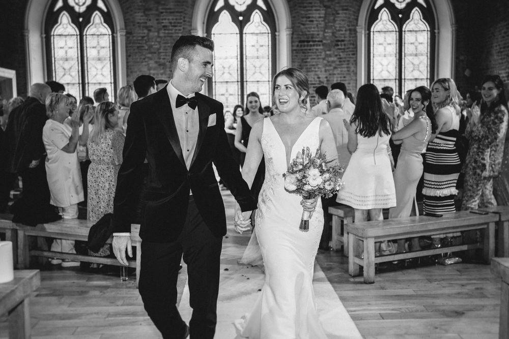 Couple celebrating while walking down church aisle after wedding ceremony.