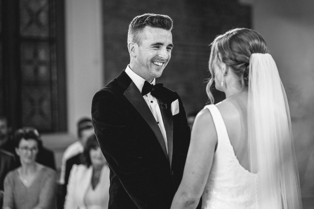 Emotional moment during wedding ceremony in historic brick chapel with gothic windows.