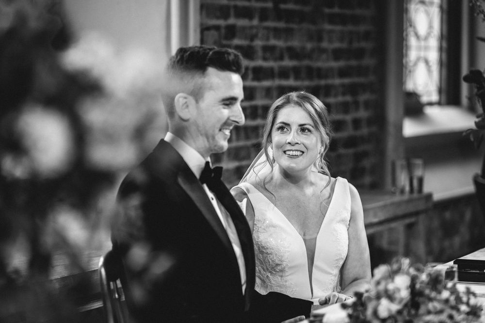 Romantic wedding ceremony moment in historic brick chapel with elegant decor and lighting.