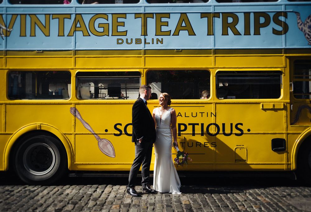 Couple poses in front of yellow vintage Dublin tea tours bus.