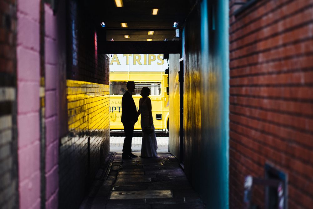 Silhouettes of couple in colorful urban tunnel with yellow lighting.